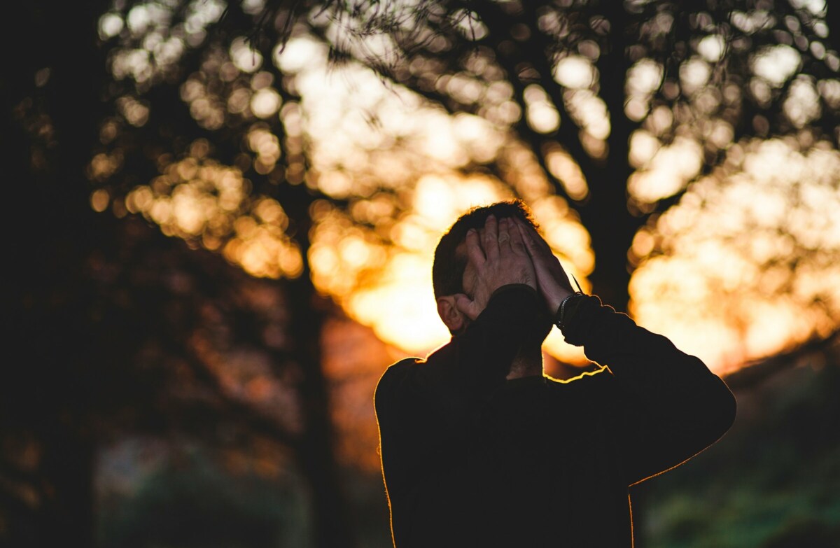 Man met handen voor zijn gezicht bij zonsondergang - Image: Unsplashed | Francisco Moreno